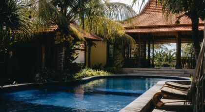 Relax by a luxurious tropical pool surrounded by lush palm trees under a sunny sky, perfect for summer getaways.